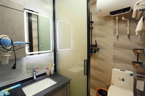 A modern bathroom with a large mirror, a sink, and a shower area.