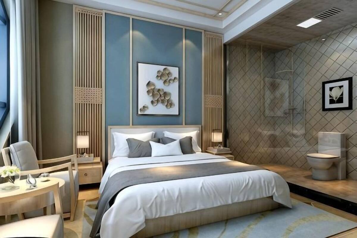 Ett modernt hotellrum med en stor säng, sängbord, ett skrivbord och en duschhörna.