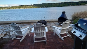 Une terrasse au bord de l’eau, dotée de fauteuils Adirondack et d’un barbecue Weber Spirit.