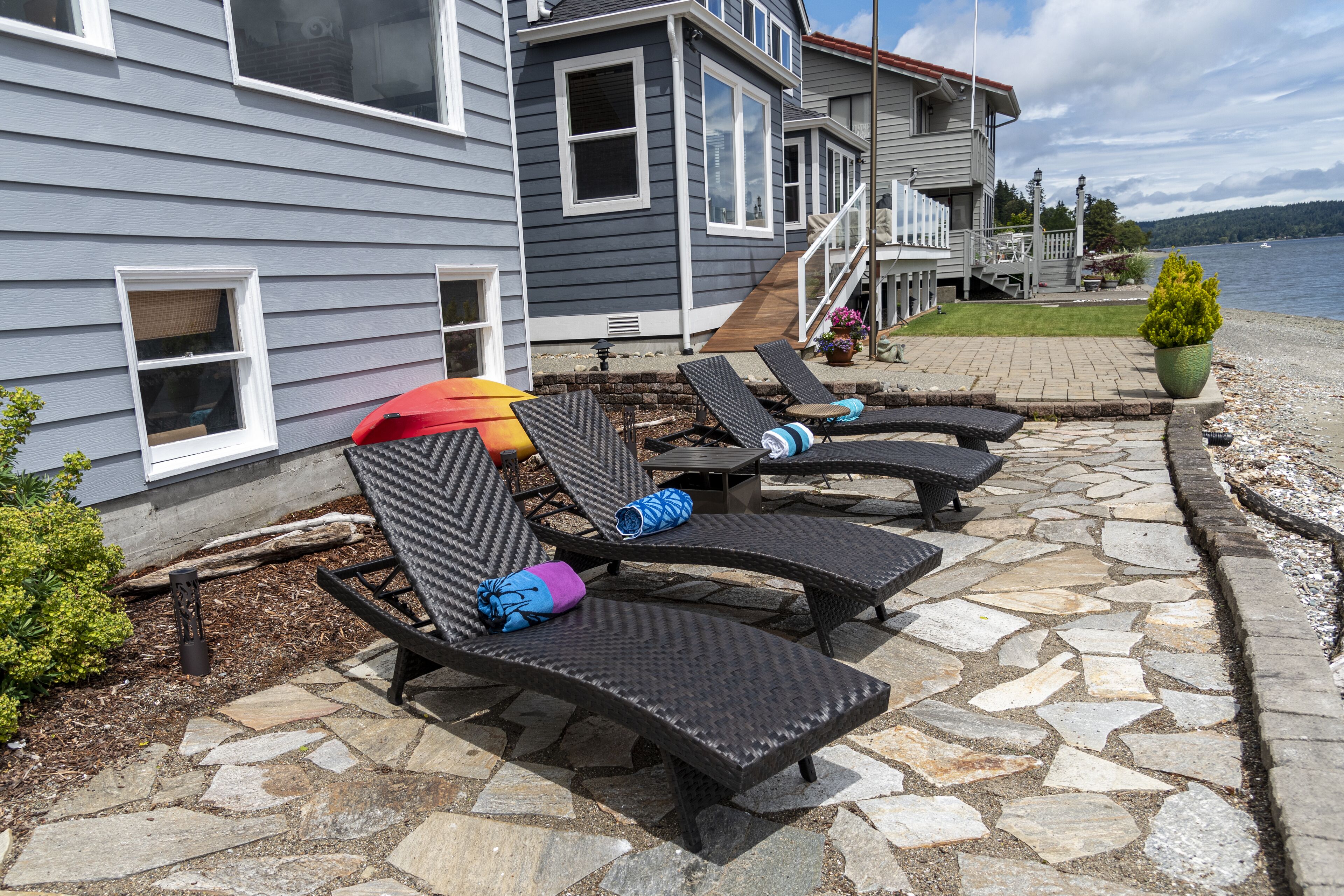 A waterfront property with a stone patio, outdoor seating, and a view of the water.