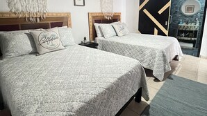 Ein Zimmer mit zwei Betten, einem Deckenventilator und einer Schiebetür zu einem Badezimmer.