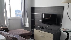 Una sala de estar moderna con un sofá, un televisor, una mesita y una lámpara.