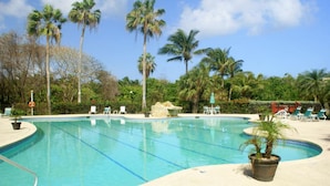 Una piscina con lettini e palme sullo sfondo.