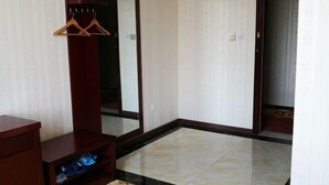 A hotel room with a wooden wardrobe, a mirror, and a tiled floor.