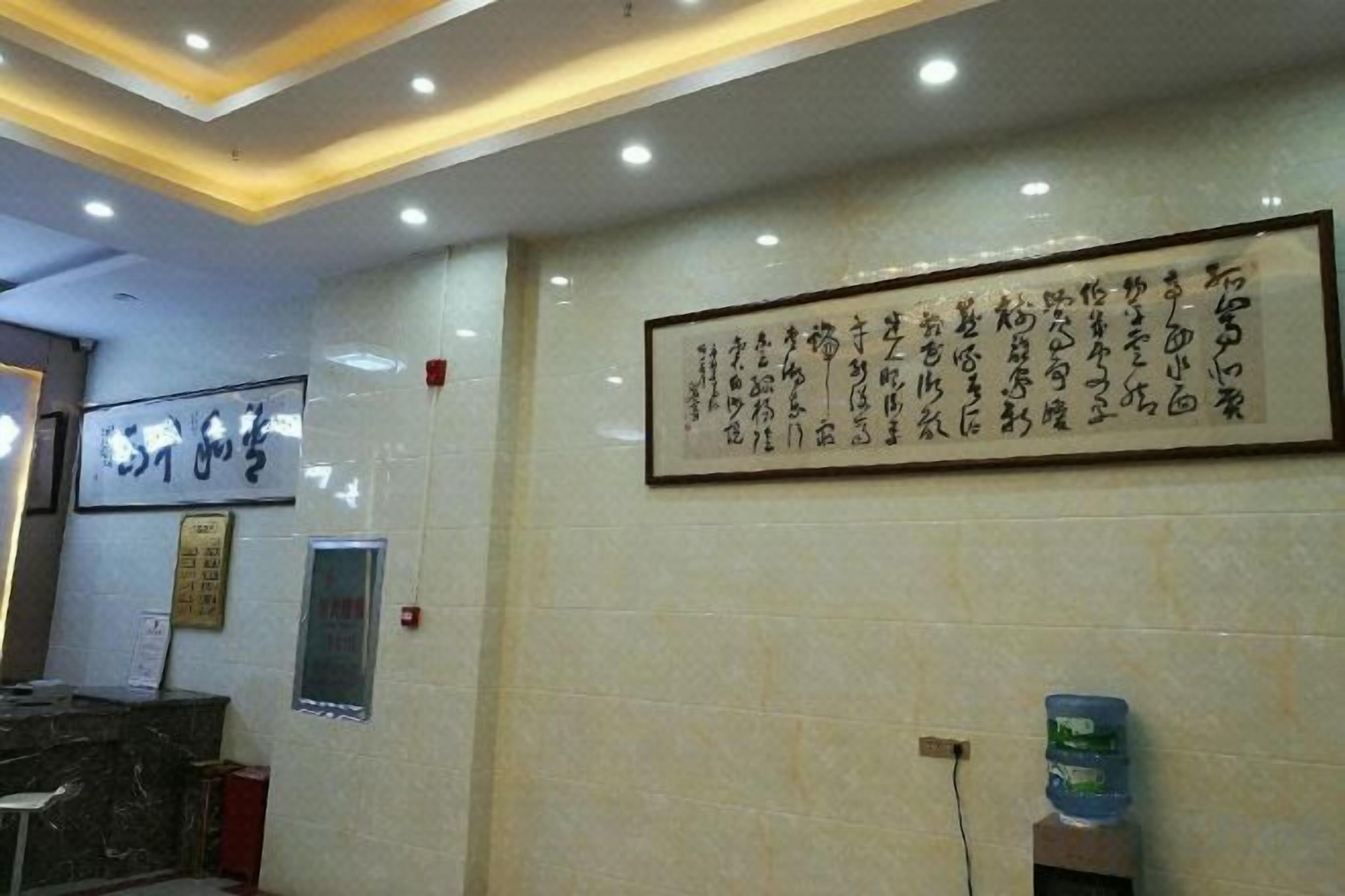 A reception area with a reception desk, a framed calligraphy piece on the wall, and a water dispenser.