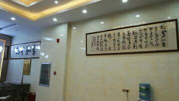 A reception area with a reception desk, a framed calligraphy piece on the wall, and a water dispenser.