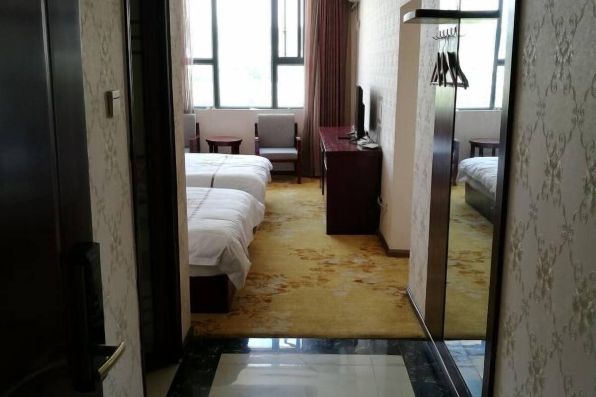 A hotel room with a bed, a desk, a chair, and a wardrobe.