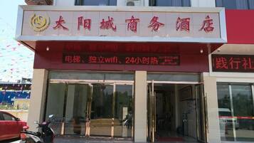 A hotel entrance with a sign indicating amenities such as wifi and 24-hour hot water.