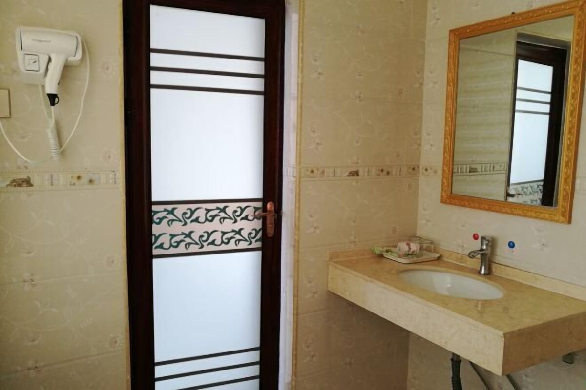 A bathroom with a white sink, a mirror with a gold frame, and a hairdryer on the wall.