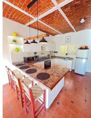 A kitchen with a central island, red brick ceiling, white cabinets, and a tiled floor. - Sol 🌞 Nayar Department, complete and remodeled (Nayarit)