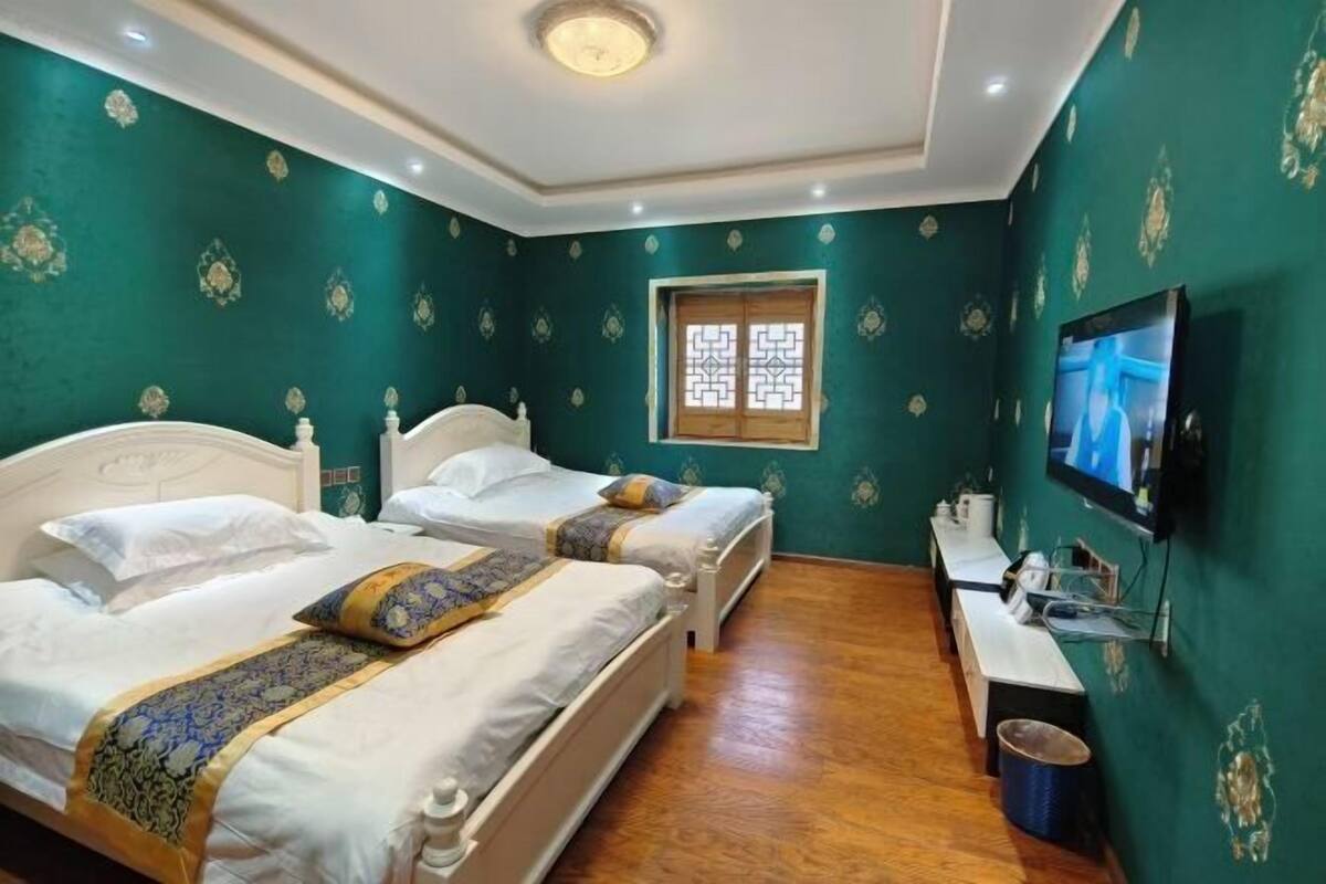 A hotel room with two beds, a television, a window, and a desk.