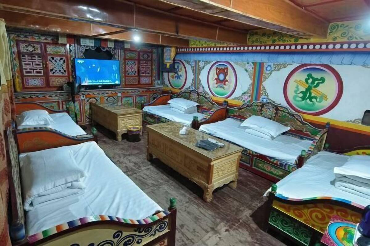 A traditional room with four beds, a wooden chest, and colorful wall decorations.