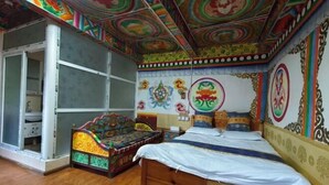 Una habitación con una cama de madera, decoraciones llamativas en las paredes y una puerta entreabierta que da a otra estancia.
