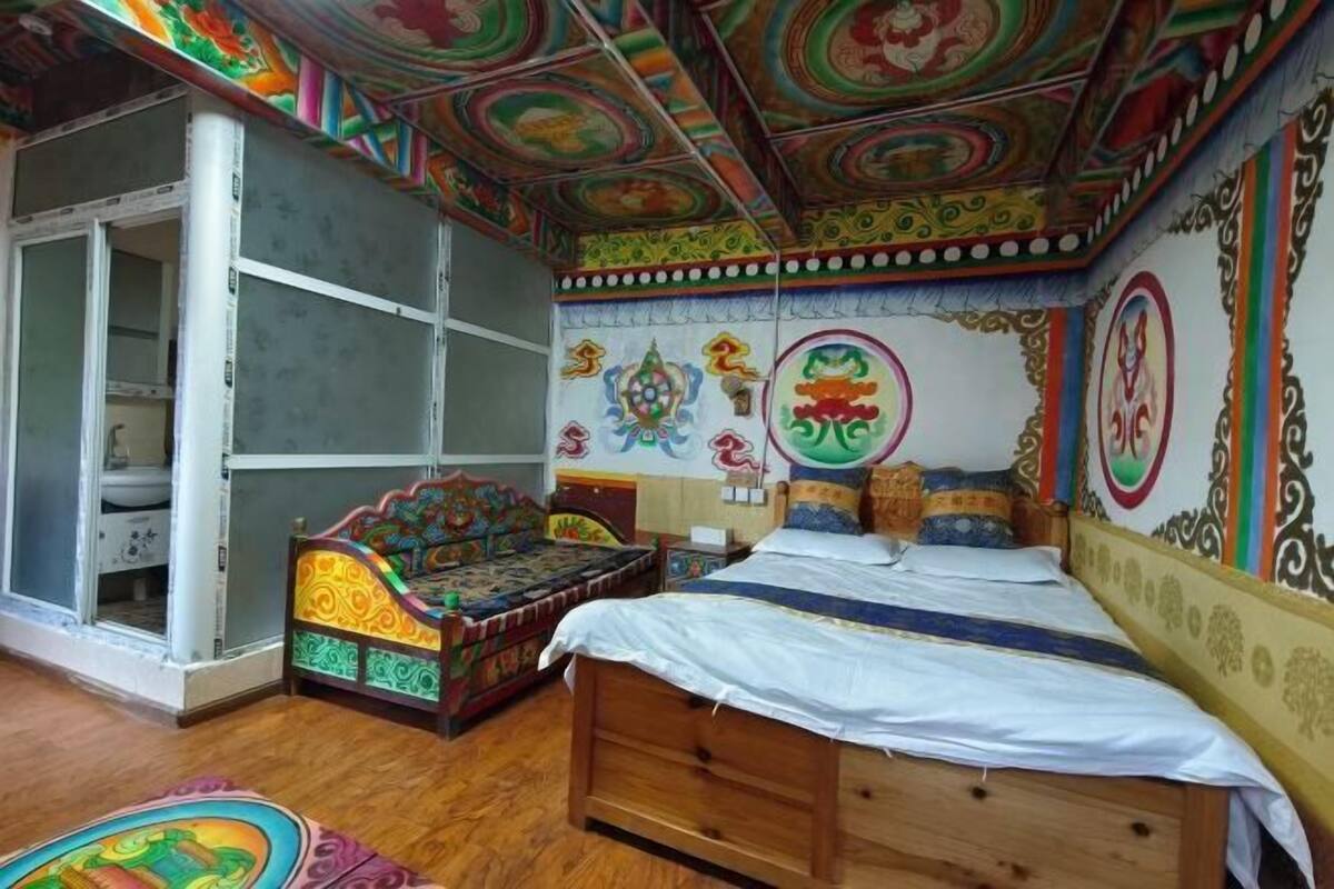 A room with a wooden bed, colorful wall decorations, and a partially open door leading to another room.