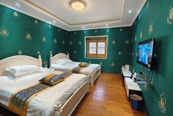 Une chambre avec deux lits, une télévision et une fenêtre agrémentée d’un paravent décoratif.