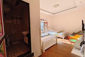 Une chambre avec deux lits, un petit bureau et une salle de bain équipée de toilettes et d’un lavabo.