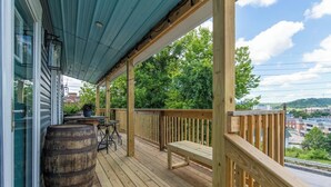 A wooden deck with a view of a cityscape, a wooden bench, and a table with chairs.