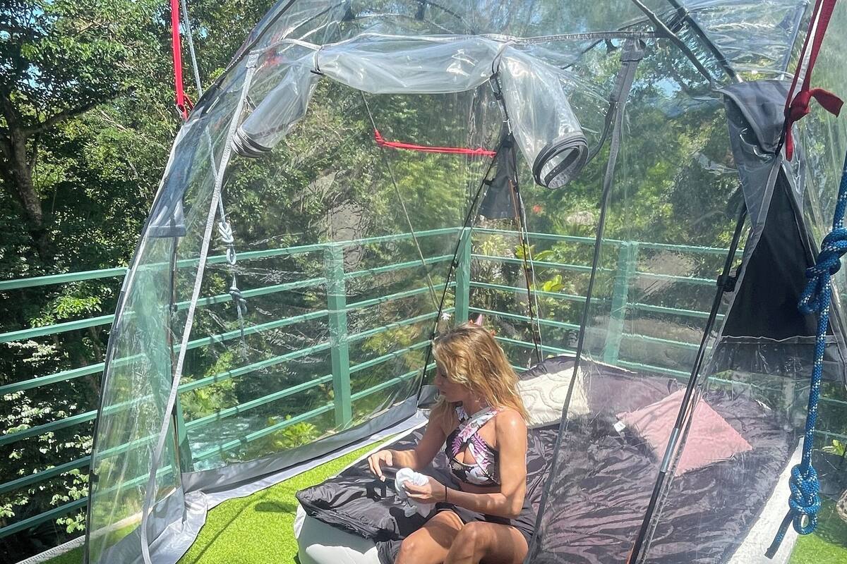 Une structure en forme de dôme transparent, dotée d’un siège rembourré à l’intérieur, et entourée d’un gazon artificiel vert.