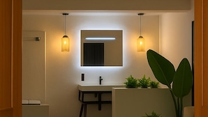 Un baño moderno con espejo, lavamanos y dos lámparas colgantes.