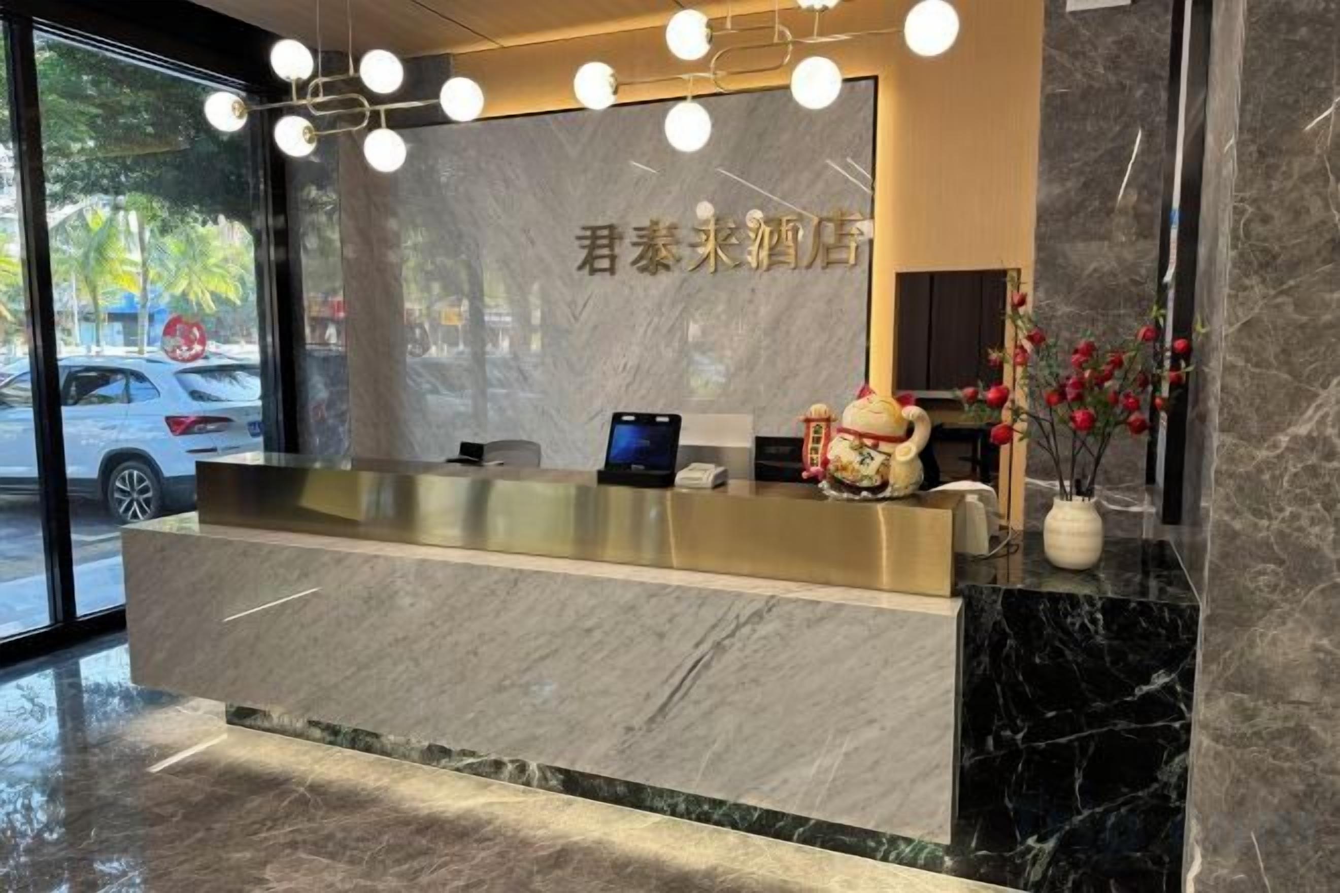 A hotel reception desk with a marble counter, a digital screen, and a vase with flowers.
