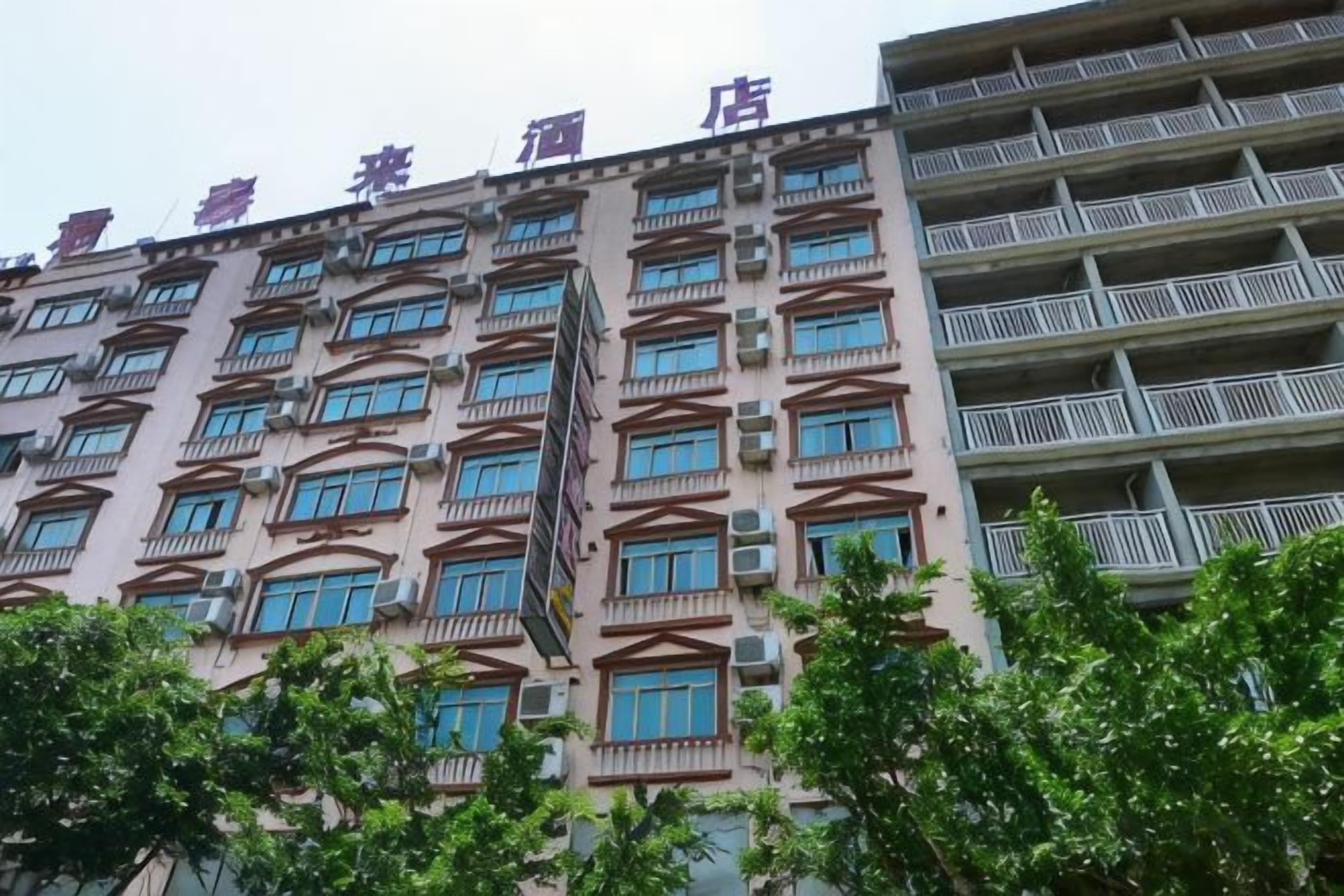 A multi-story hotel with balconies, a central staircase, and a row of windows on each floor.
