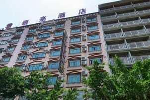 Un hotel de varios pisos con balcones, una escalera central y una fila de ventanas en cada planta.