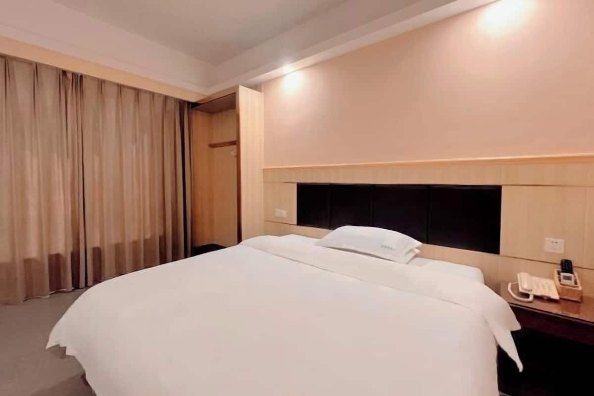 A hotel room with a bed, a bedside telephone, and a curtain.