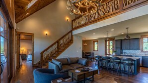 Un vaste espace de vie comprenant un grand canapé en cuir, une table basse et un escalier au style rustique.