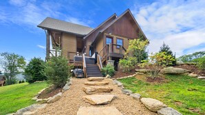 Une maison en bois à deux étages, avec un chemin de pierre menant à la porte d’entrée.