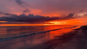 A sunset over a beach with calm waves and a clear sky. - Modern Oceanview Heated pool overlooking Mad Beach (Madeira Beach)