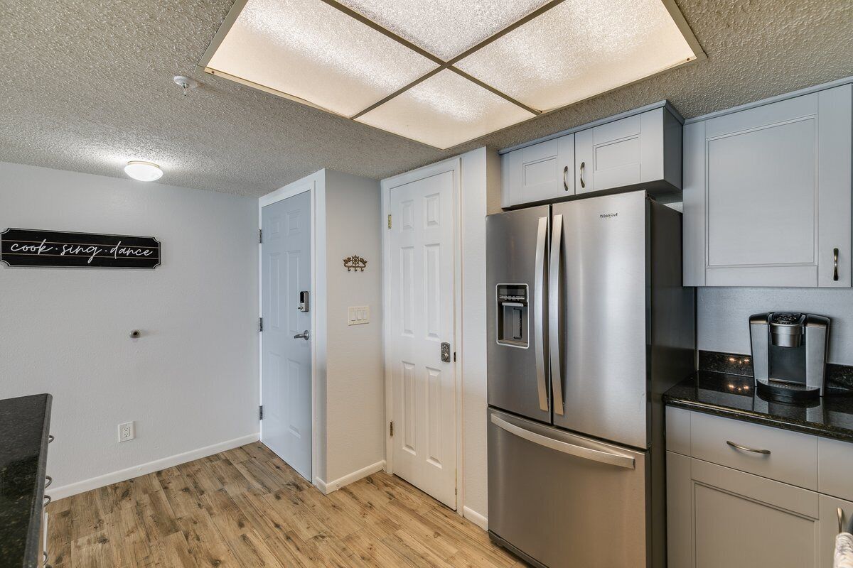 A kitchen with a stainless steel refrigerator, a coffee maker, and a wall-mounted light fixture.