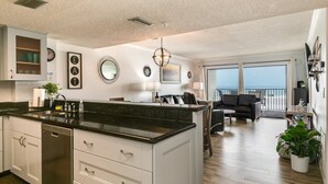 A modern kitchen with a large island, white cabinetry, and a view to the living area. - Modern Oceanview Heated pool overlooking Mad Beach (Madeira Beach)