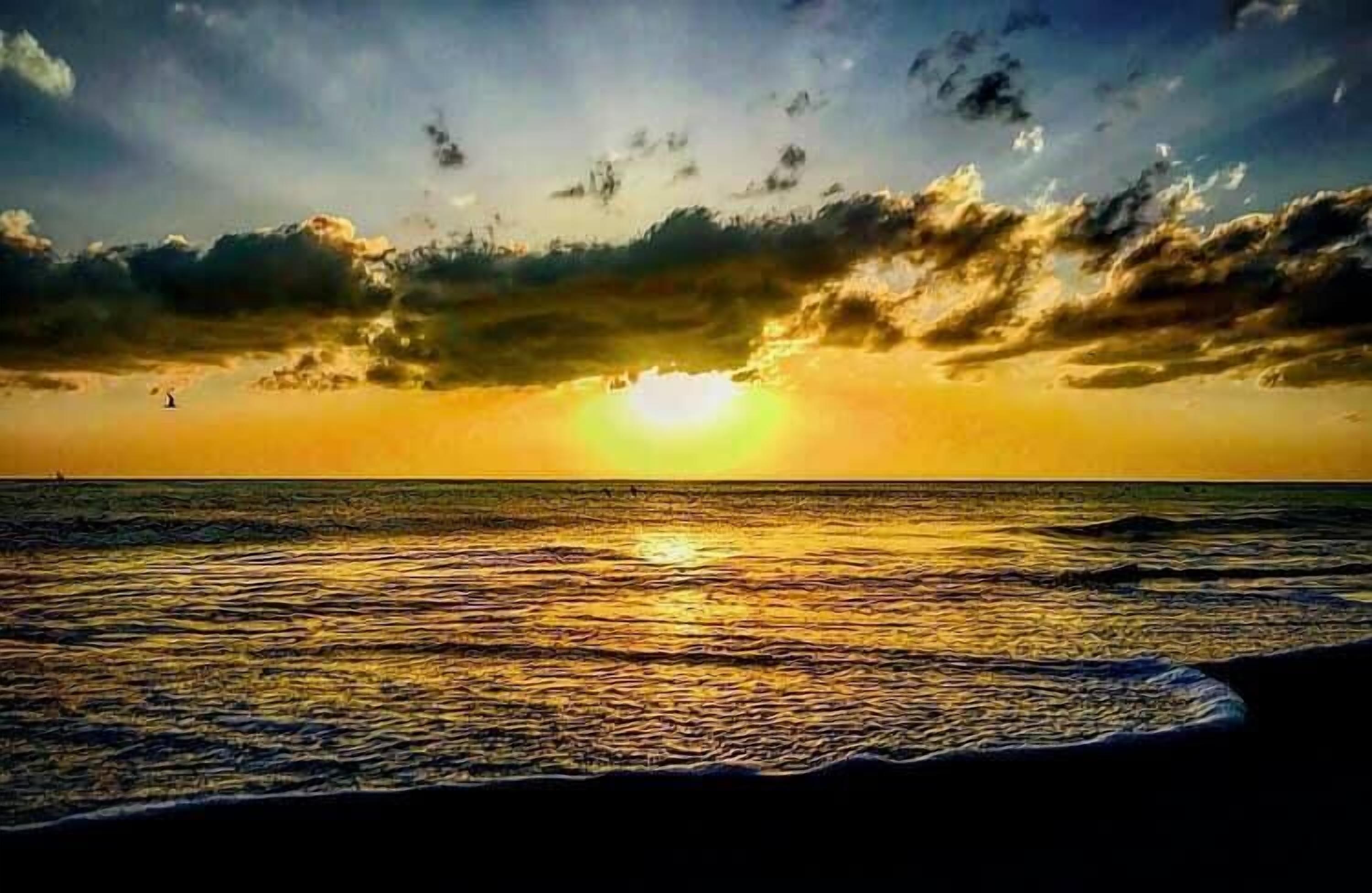 Un atardecer sobre el océano con nubes en el cielo.