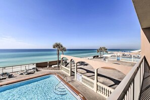 A pool area with a view of the ocean, lounge chairs, and palm trees. - Beachfront Condo w/Pool, Hot Tub & Beach Chairs Included (Panama City Beach)