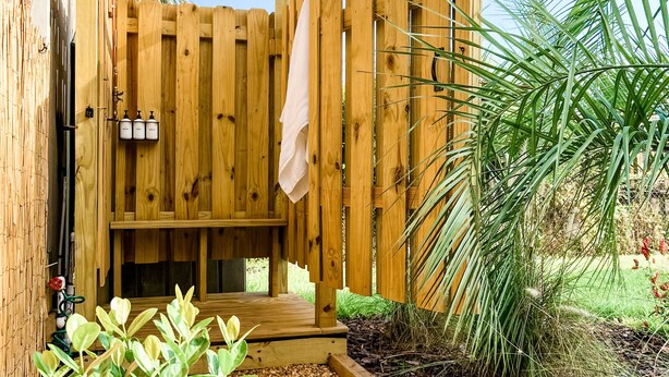 A wooden deck with a wooden fence, a small bench, and a pathway leading to a wooden structure. - Newly Renovated Home w/Outdoor Shower, Pool & Tiki Hut!  (Crystal River)