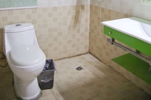 A bathroom with a toilet, a trash bin, and a sink. - Xuancheng Tianzi Business Hotel (Xuancheng)