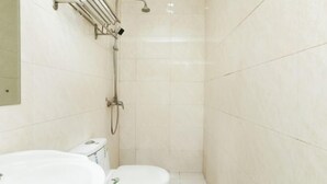 Un baño pequeño y limpio con inodoro, lavamanos y ducha.