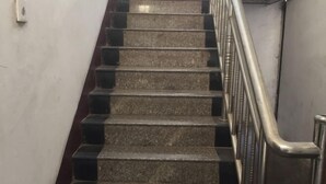 Una escalera con escalones de granito y barandillas de metal.