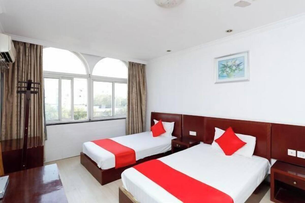 A hotel room with two beds, a desk, and a window with curtains.