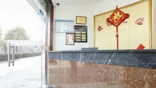 Un área de recepción con mostrador de mármol, una placa en la pared y un elemento decorativo rojo.