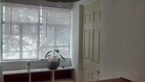 Een kamer met een raam, een deur en een plant op een plank.