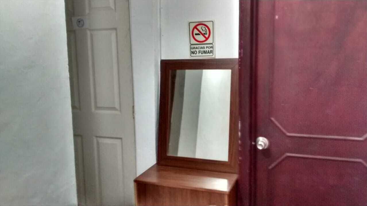 A door with a no-smoking sign and a small mirror above it.
