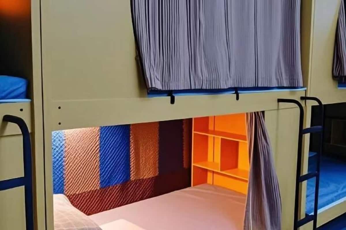 A bunk bed with a striped headboard and a shelf below.