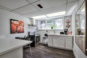 A modern kitchen with white cabinets, a stainless steel stove, and a large window providing natural light.