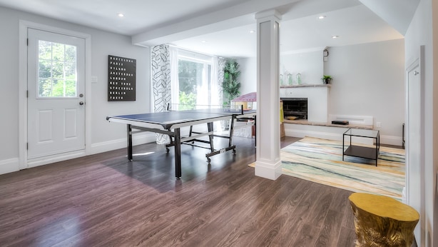 Una sala de estar moderna con mesa de ping pong, chimenea y vistas al exterior.