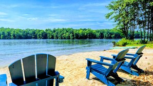 Un cadre idyllique au bord du lac, avec des fauteuils Adirondack et une table installés sur une plage de sable.
