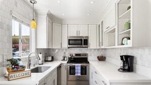 A modern kitchen with white cabinetry, a stainless steel microwave, an oven, and a coffee maker. - Scott Place - Amazing location, heated pool, vibrant space awaits! (Scottsdale)