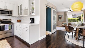 A modern kitchen with white cabinetry, a built-in microwave, and a stove. There is a dining area with a round table and chairs. - Scott Place - Amazing location, heated pool, vibrant space awaits! (Scottsdale)