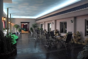 A spacious indoor area with a long table and chairs, potted plants, and a view of a building in the background. - Borrman (hangzhou xianghu) (Hangzhou)
