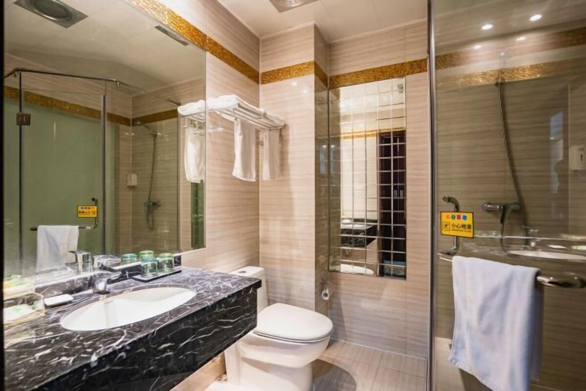 A modern bathroom with a dual sink vanity, a toilet, a glass-enclosed shower, and a large mirror.